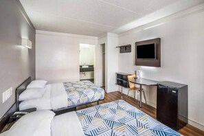 A hotel room with two beds, a desk, a chair, a TV, and a small kitchenette. - 2 Full Beds | Non - Smoking (Dallas)