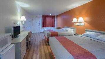 A hotel room with a bed, a desk, a television, and a door leading to another room.