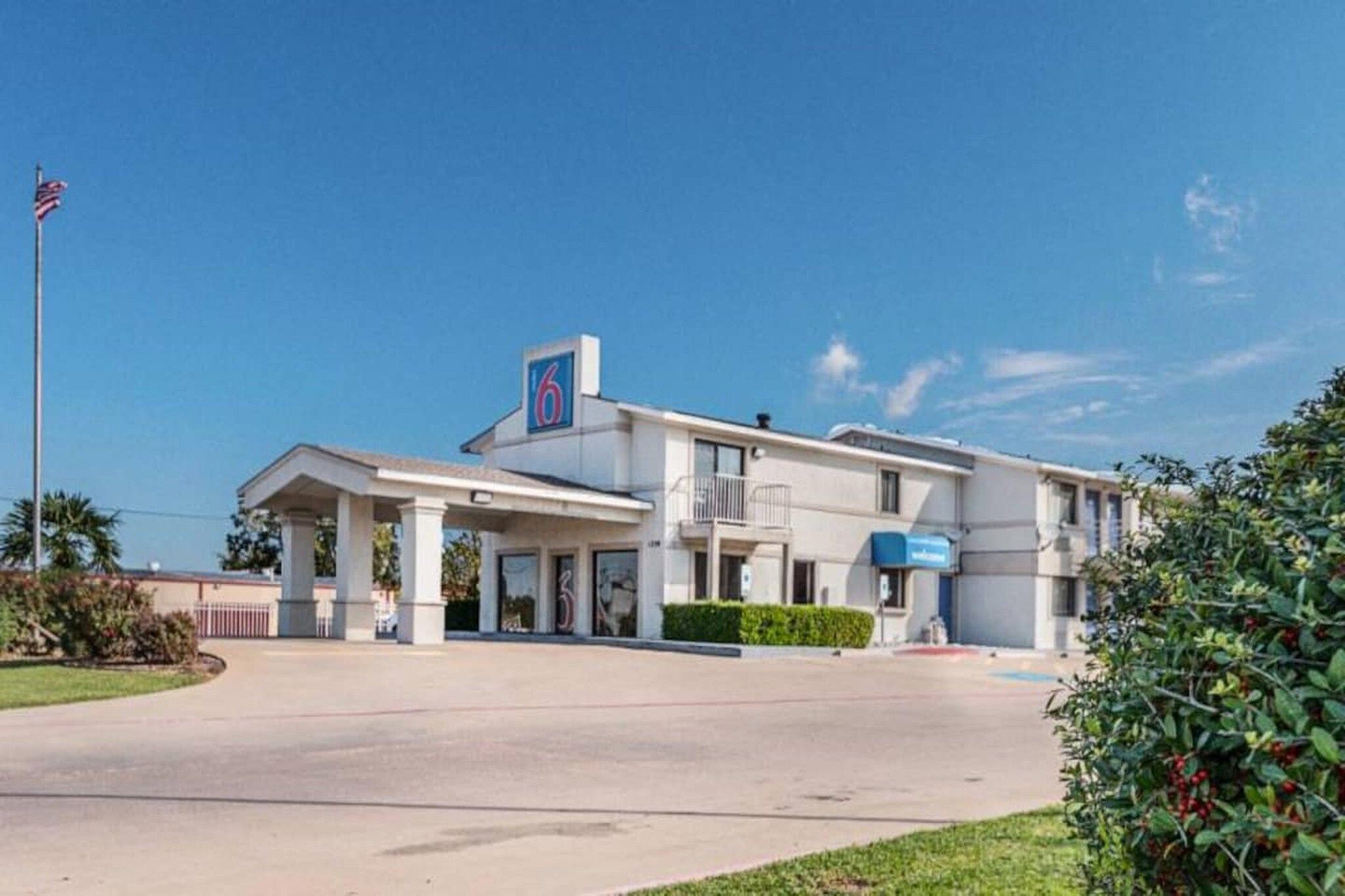 Un motel composé d’un bâtiment d’un seul étage, d’un porche couvert et d’un mât pour drapeau.