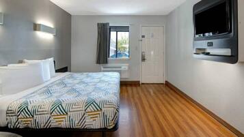 Ein Hotelzimmer mit einem Bett, einem Fernseher, einem Fenster mit Vorhängen und einer Tür.