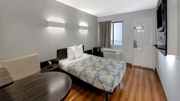 Een hotelkamer met een bed, een bureau, een stoel, een televisie en een raam met gordijnen.