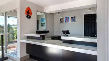 A modern reception desk with a digital screen, a black door, and framed pictures on the wall.