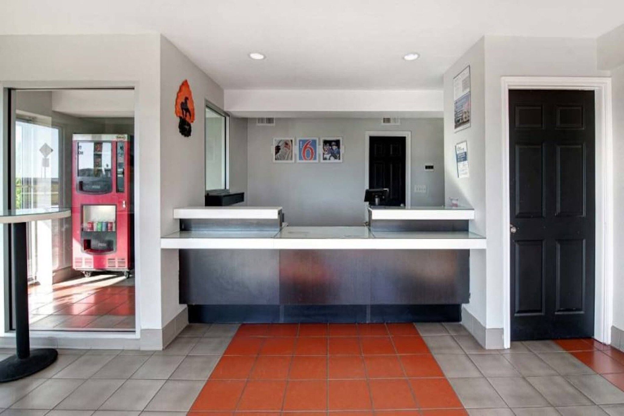 A reception area with a counter, a black door, and a red-tiled floor.