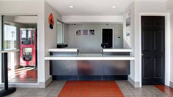 A reception area with a counter, a black door, and a red-tiled floor.