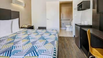Une chambre d’hôtel comprenant un lit, un bureau, une chaise, une salle de bain et une kitchenette.