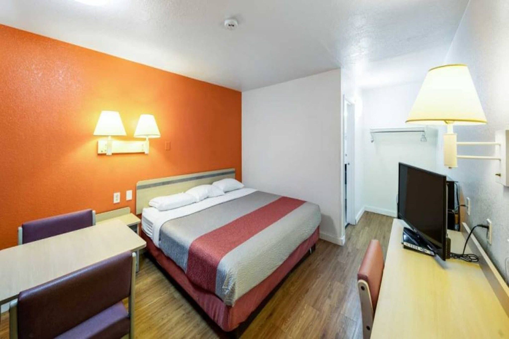 Camera d'albergo con un letto, una scrivania, una sedia e un televisore.
