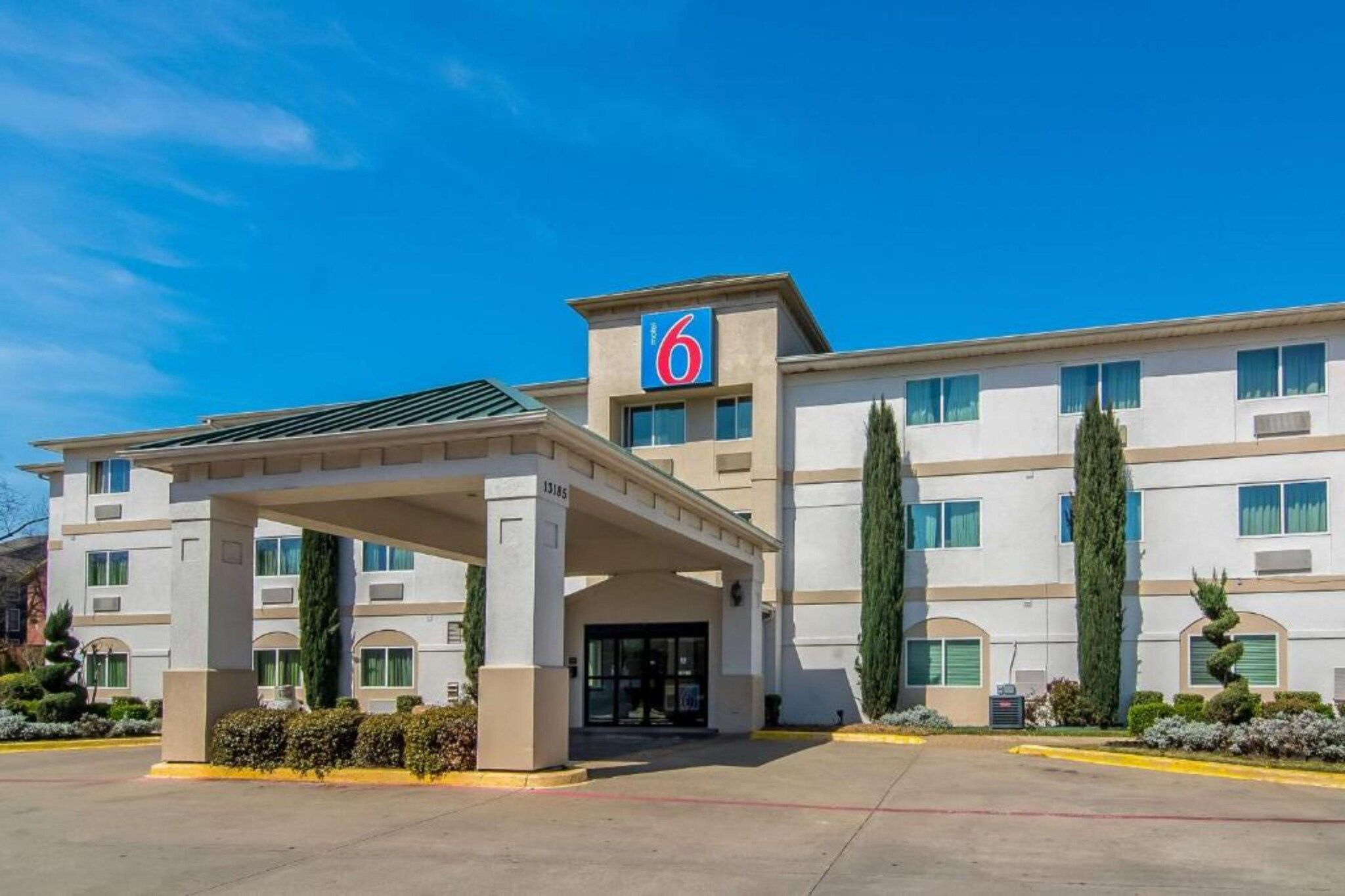A hotel with a prominent '6' sign, a covered entrance, and a symmetrical facade with multiple windows.