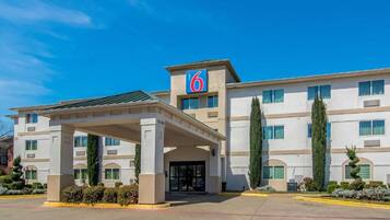 A hotel with a prominent '6' sign, a covered entrance, and a symmetrical facade with multiple windows.
