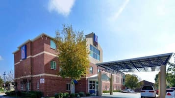 A multi-story building with a parking area and a covered entrance.