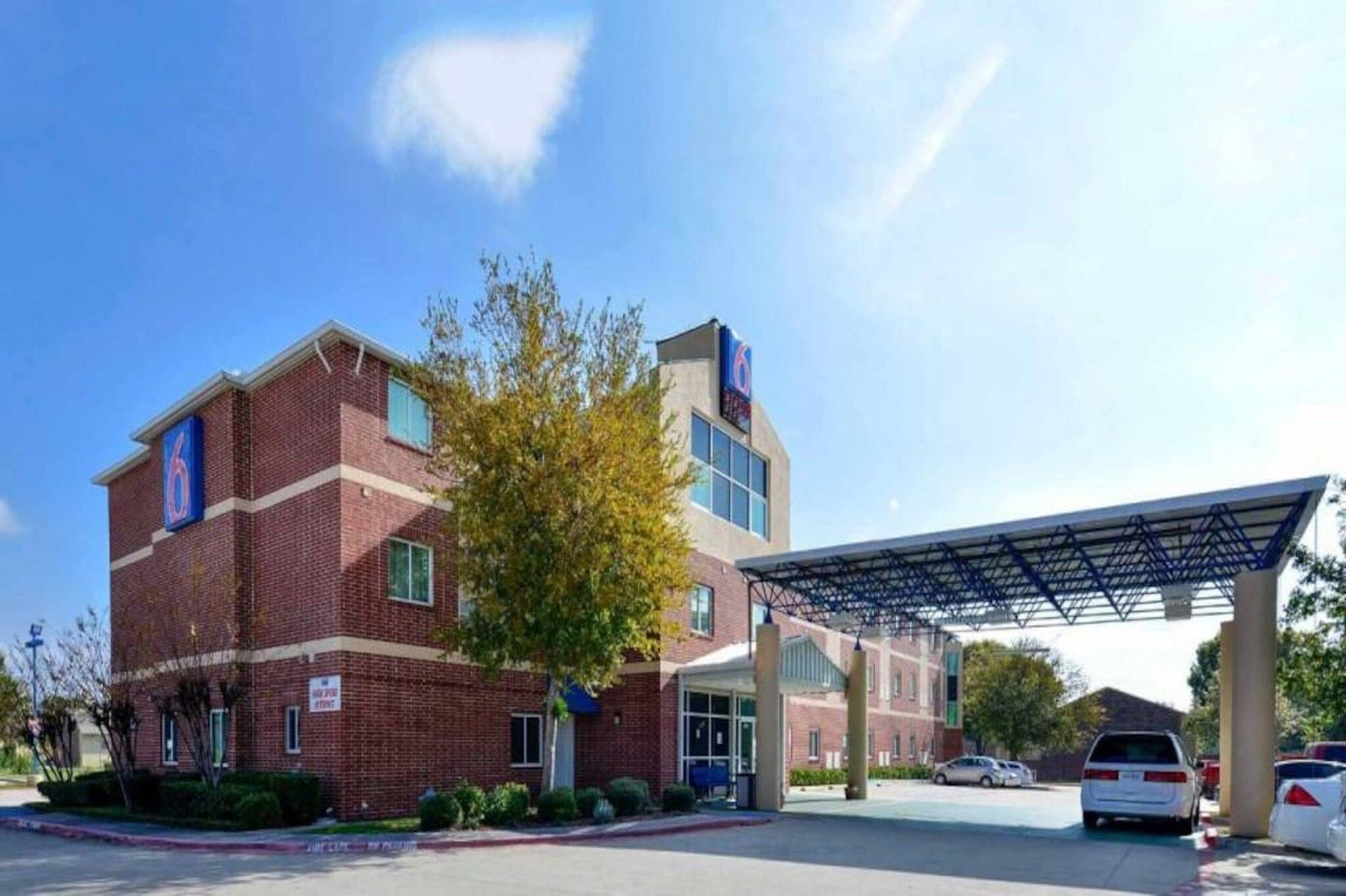 A multi-story building with a parking area and a covered entrance.