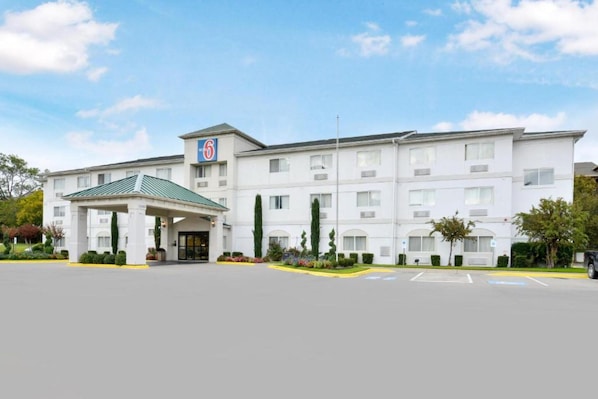 A multi-story hotel with a central entrance, a covered parking area, and a clear sky. - 2 Queen Beds | Non-Smoking (Dallas)