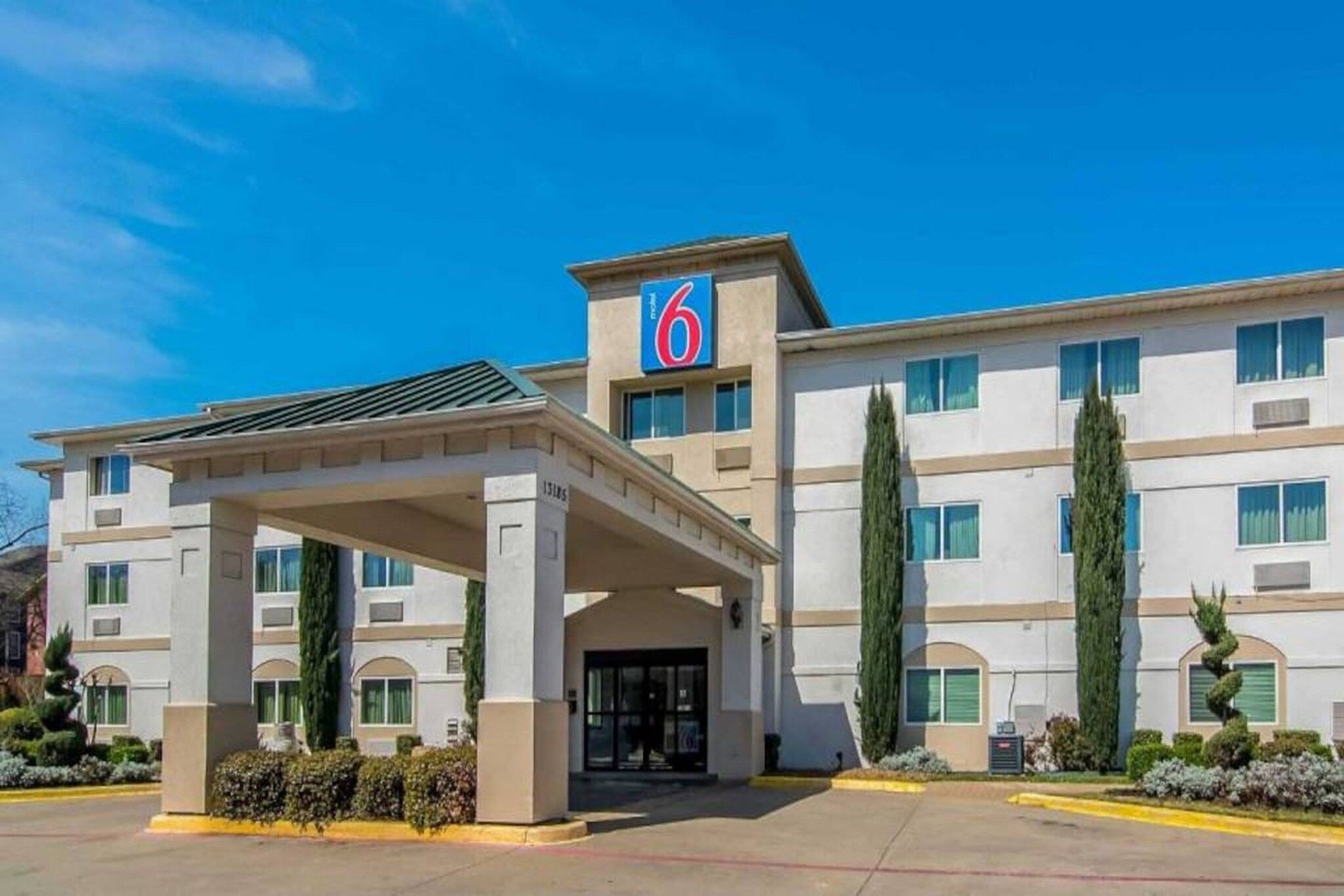 A multi-story hotel with a covered entrance, a prominent '6' sign, and a parking lot.