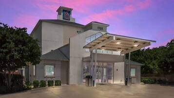 A hotel with a large entrance, a covered waiting area, and a number '1720' on the building.