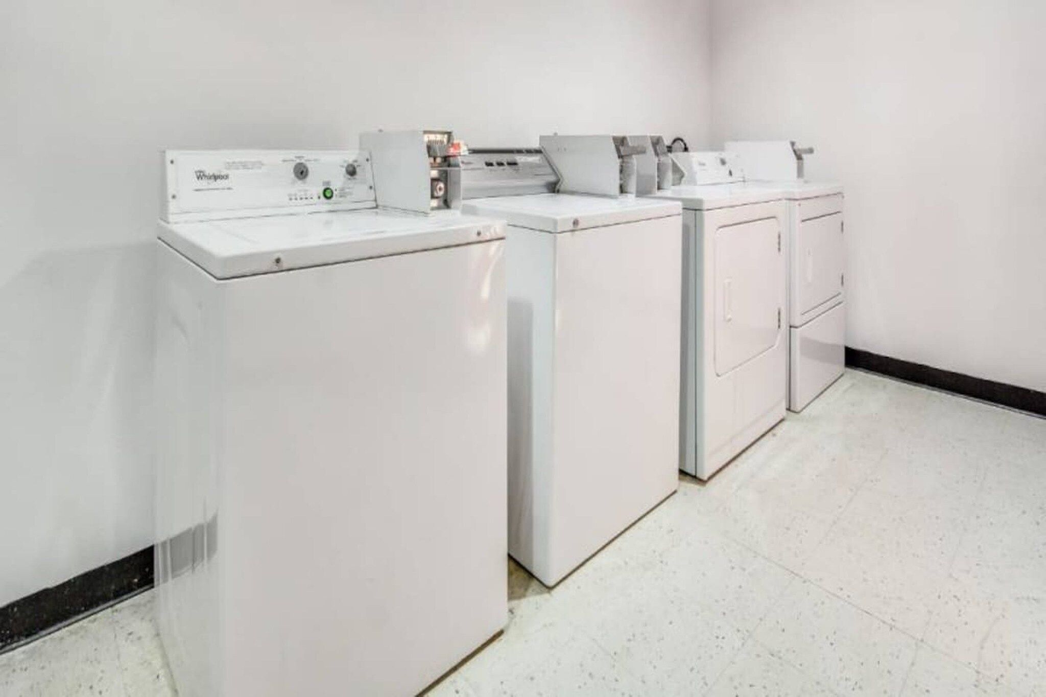 A laundry room with a front-loading washer and dryer, a utility sink, and a cabinet with a mirror.