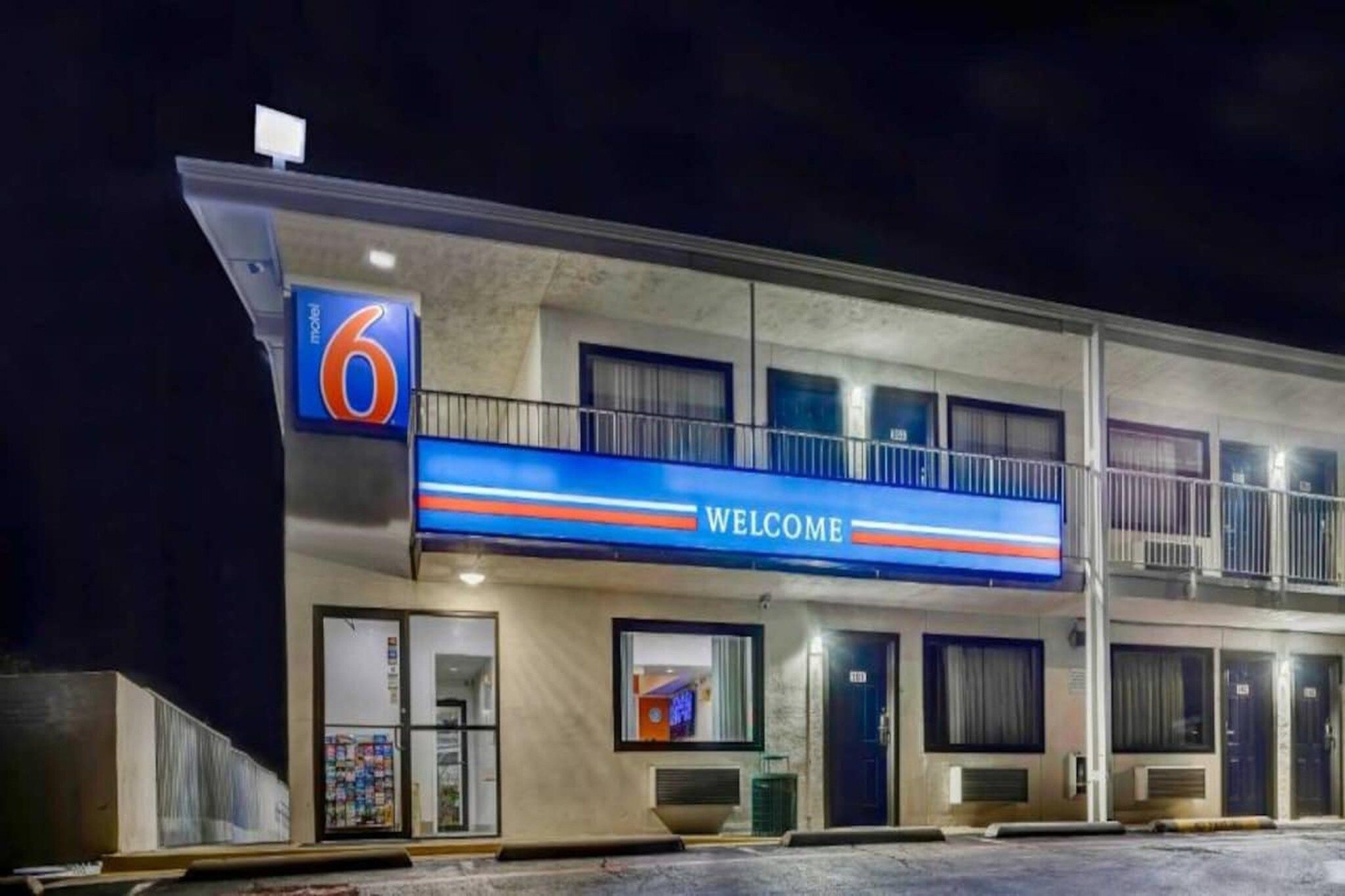 A motel with a '6' sign, a 'WELCOME' sign, and a balcony.