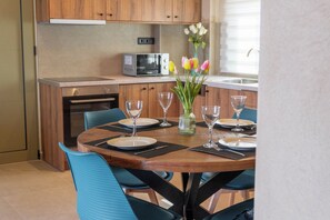 A dining area with a wooden table set for four, surrounded by blue chairs. - Amnia Villas, Be on Holidays (Rethymno)