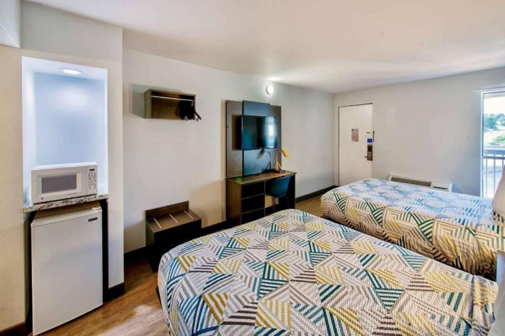 Camera d'albergo con due letti, un forno a microonde, una TV e una piccola scrivania.