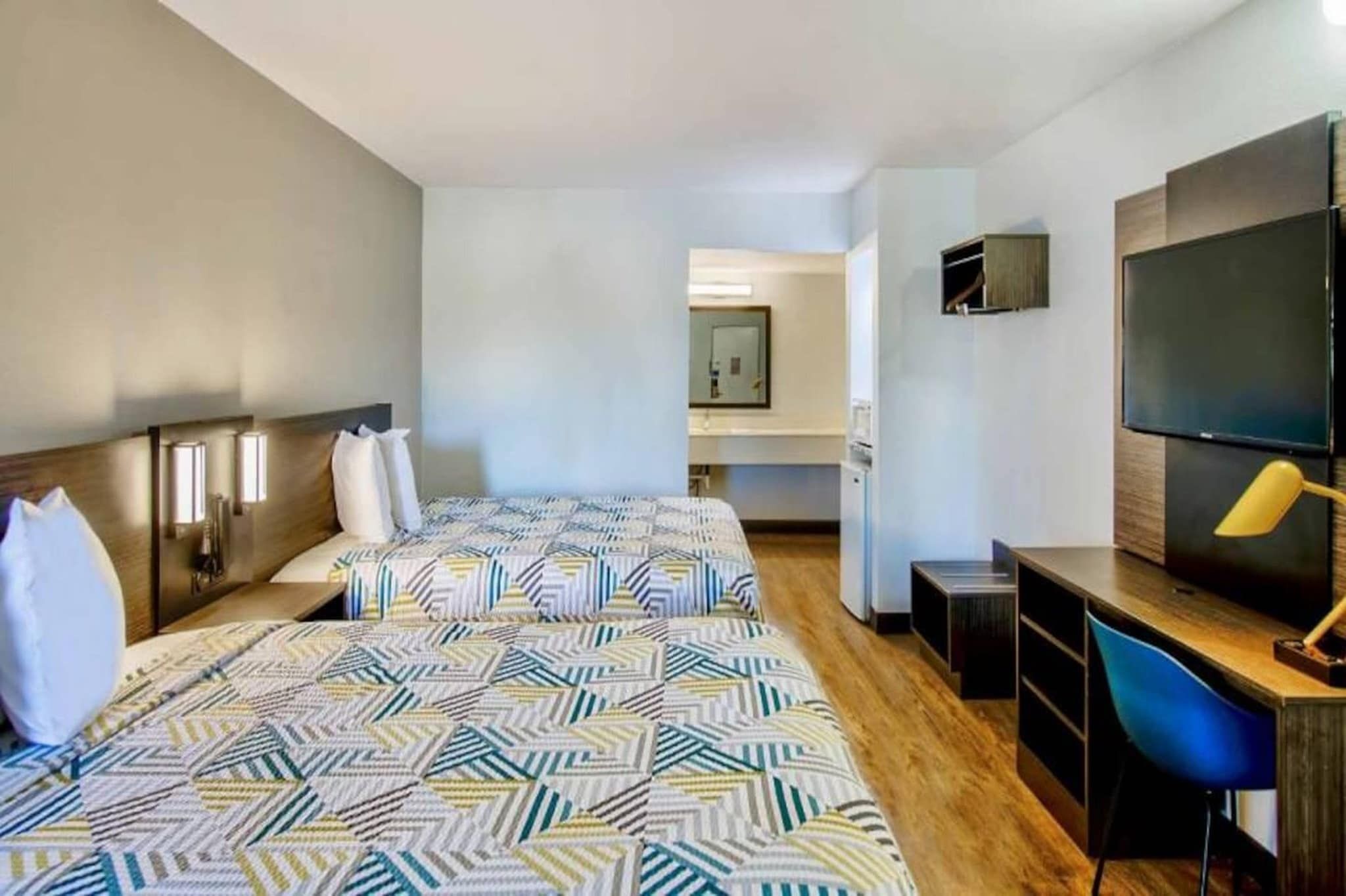 Une chambre d’hôtel avec un grand lit, un bureau, une télévision et un miroir.