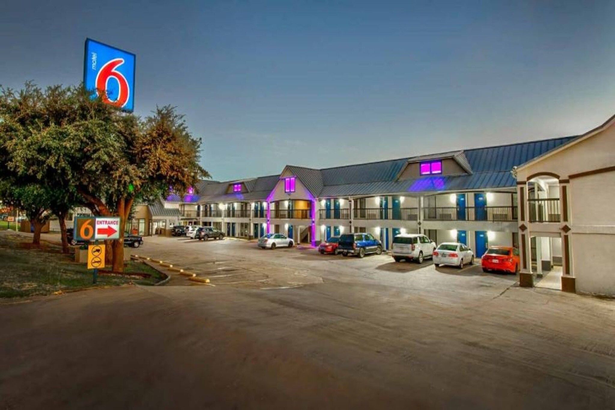 Um motel com várias vagas de estacionamento e um grande letreiro de entrada.