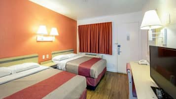 A hotel room with two beds, a television, and a door with a window.