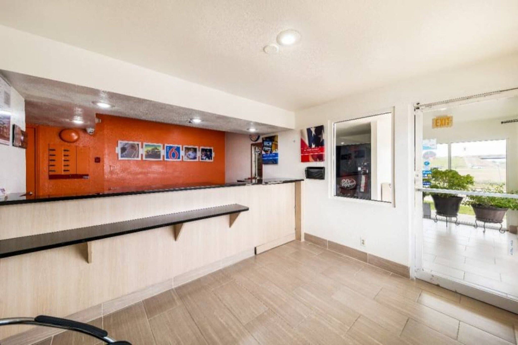A reception area with a counter, a wall-mounted phone, and a door leading to an outdoor area with potted plants.