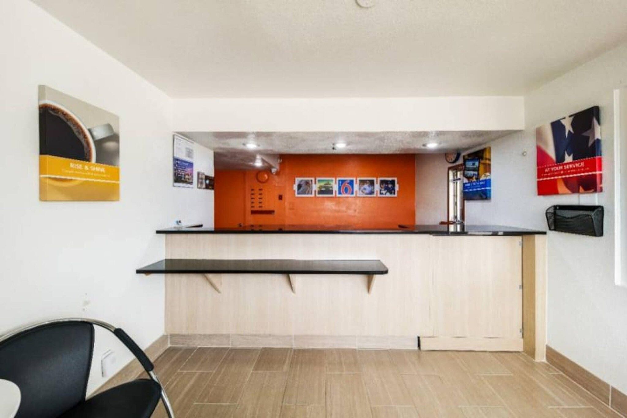 A reception area with a counter, a chair, and a wall with posters.