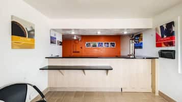 A reception area with a counter, a chair, and a wall with posters.