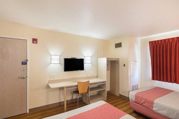 Habitació d'hotel amb llit, escriptori, cadira, televisió i armari.