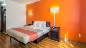 A hotel room with a bed, bedside tables, and a wall-mounted lamp.