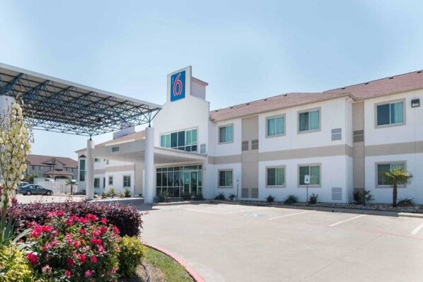 A hotel with a covered parking area, a large entrance, and a building with multiple windows. - 1 Queen Bed | Non-Smoking (Hillsboro)