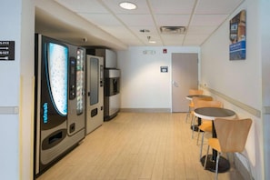 A hallway with vending machines, a water dispenser, and a seating area with tables and chairs. - 1 Queen Bed | Non-Smoking (Hillsboro)