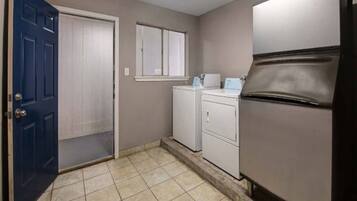 A laundry room with a blue door, a washing machine, a dryer, and a refrigerator.