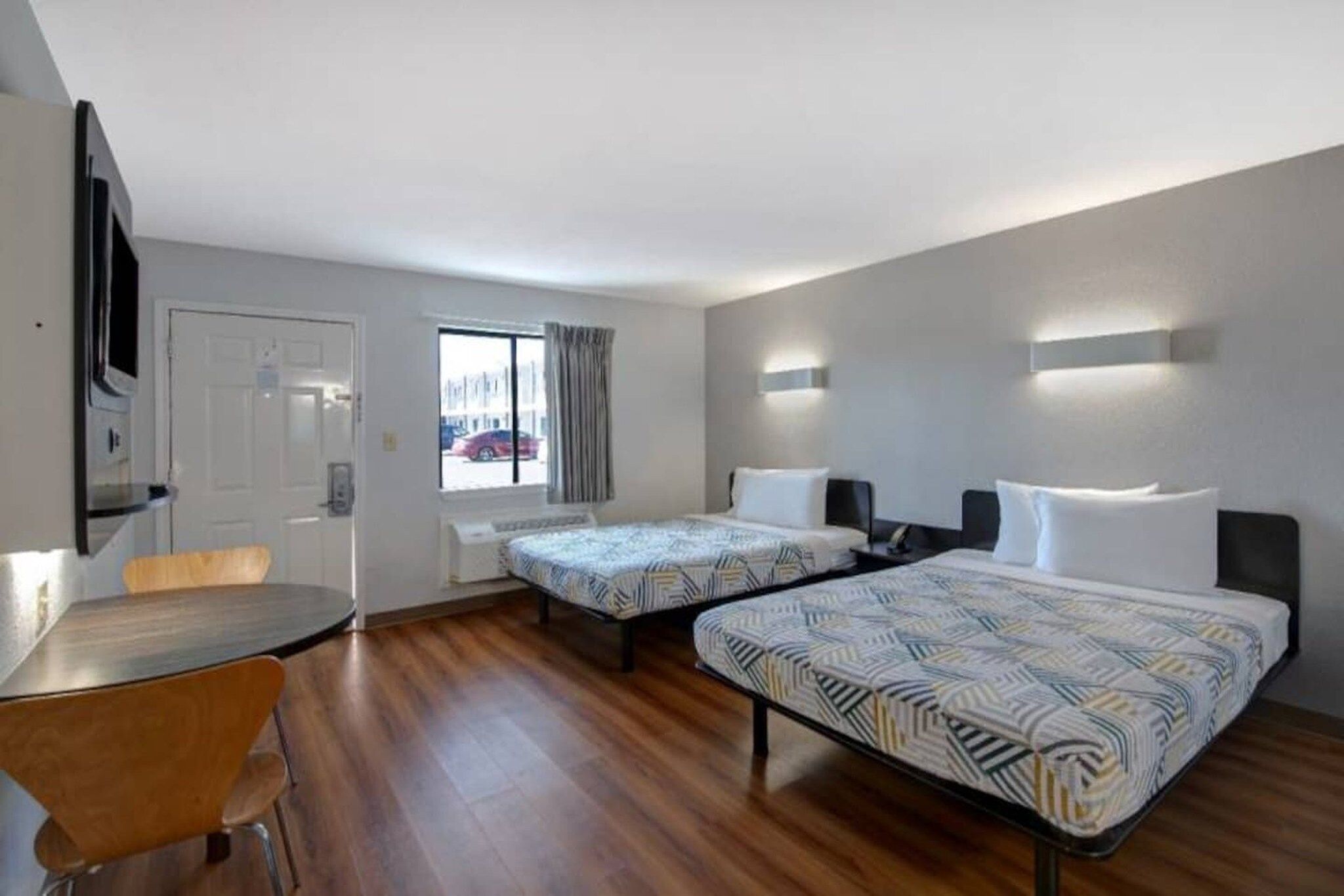 A hotel room with two beds, a desk, and a chair.