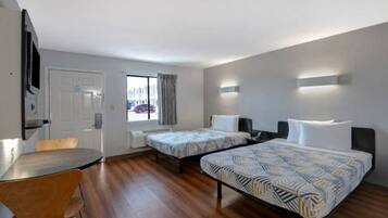 A hotel room with two beds, a desk, and a chair.