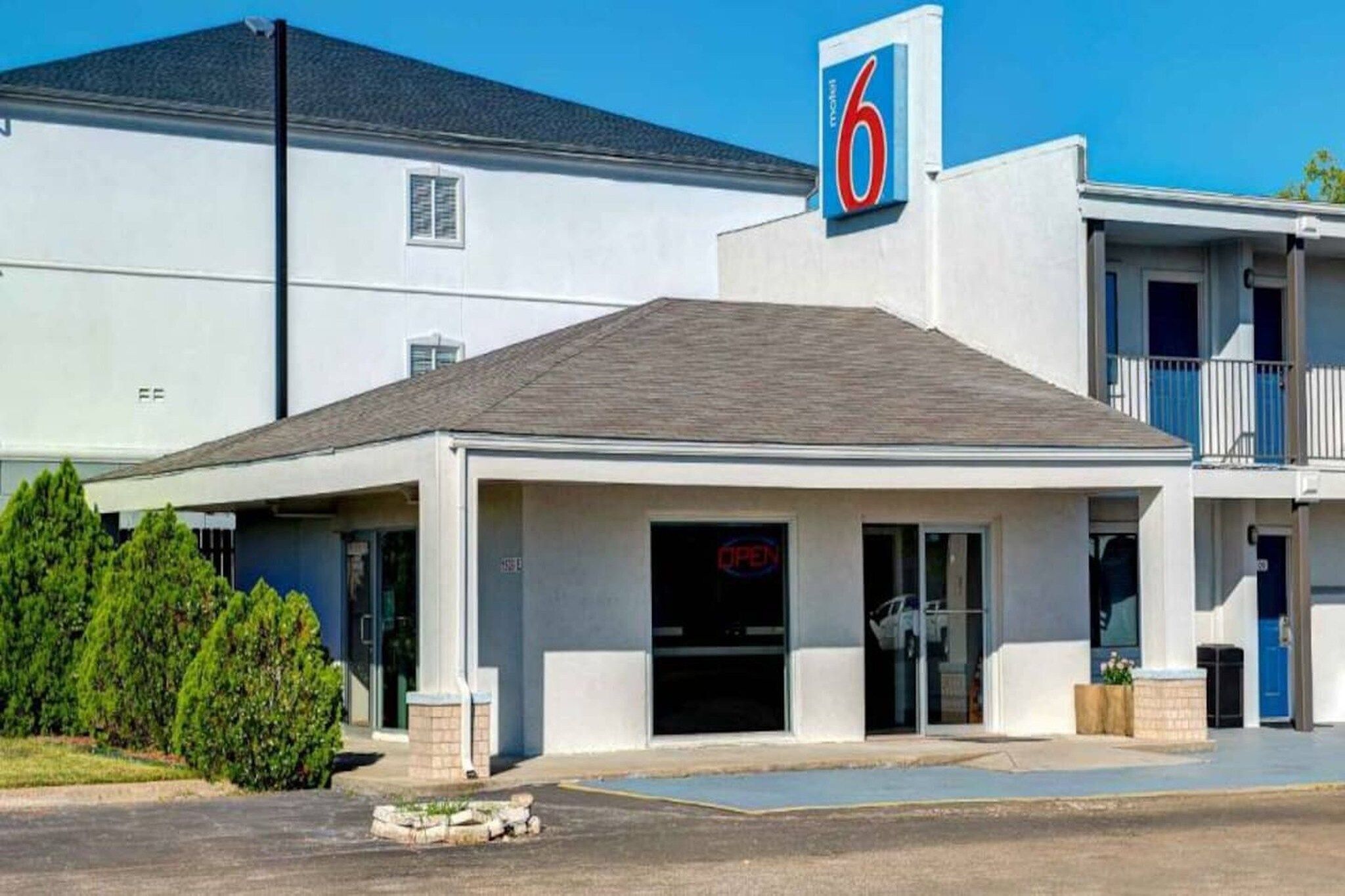 A motel with a prominent '6' sign, a covered entrance, and a parking lot.