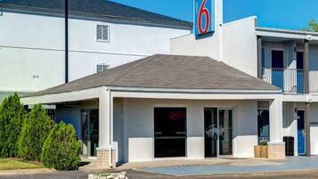 A motel with a prominent '6' sign, a covered entrance, and a parking lot.