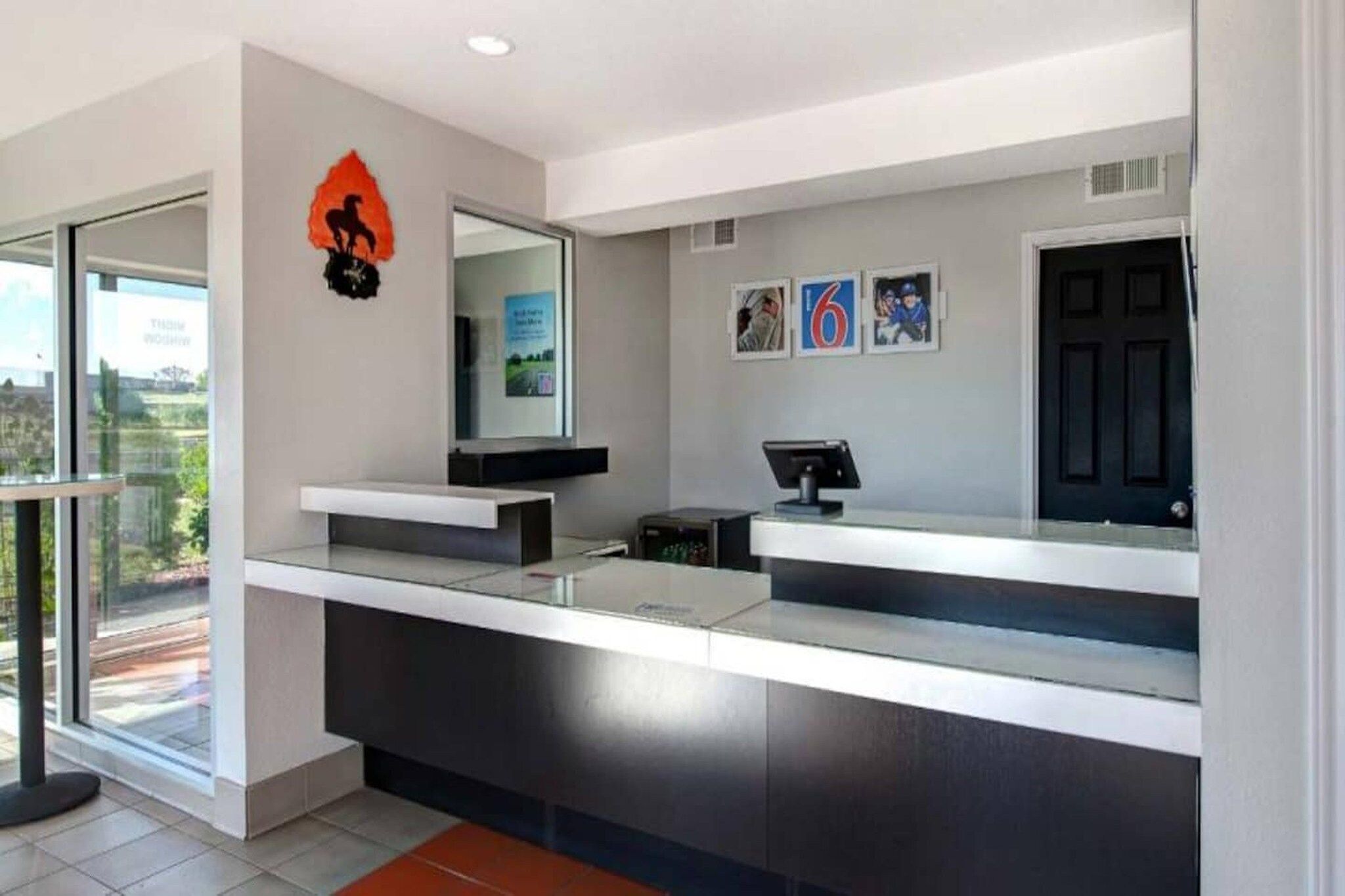 A modern reception desk with a digital screen, a black door, and framed pictures on the wall.