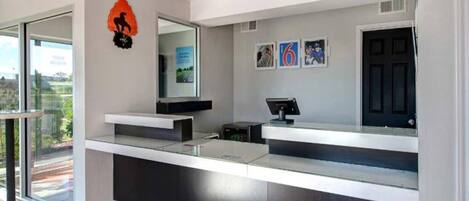 A modern reception desk with a digital screen, a black door, and framed pictures on the wall.