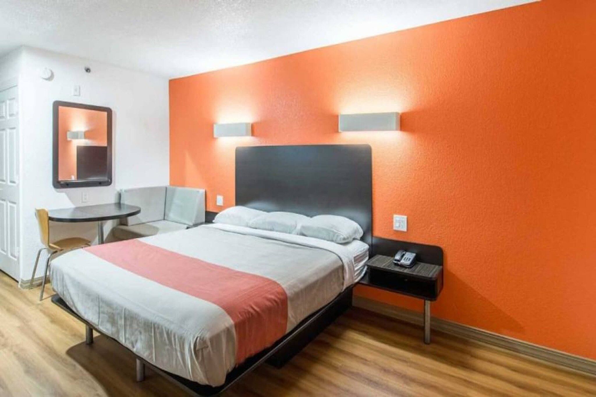 Ein Hotelzimmer mit Bett, Nachttisch, Stuhl und einem kleinen runden Tisch.