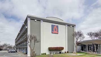Een gebouw met een opvallend nummer '6', een parkeerplaats en een klein groenstrook met struiken.