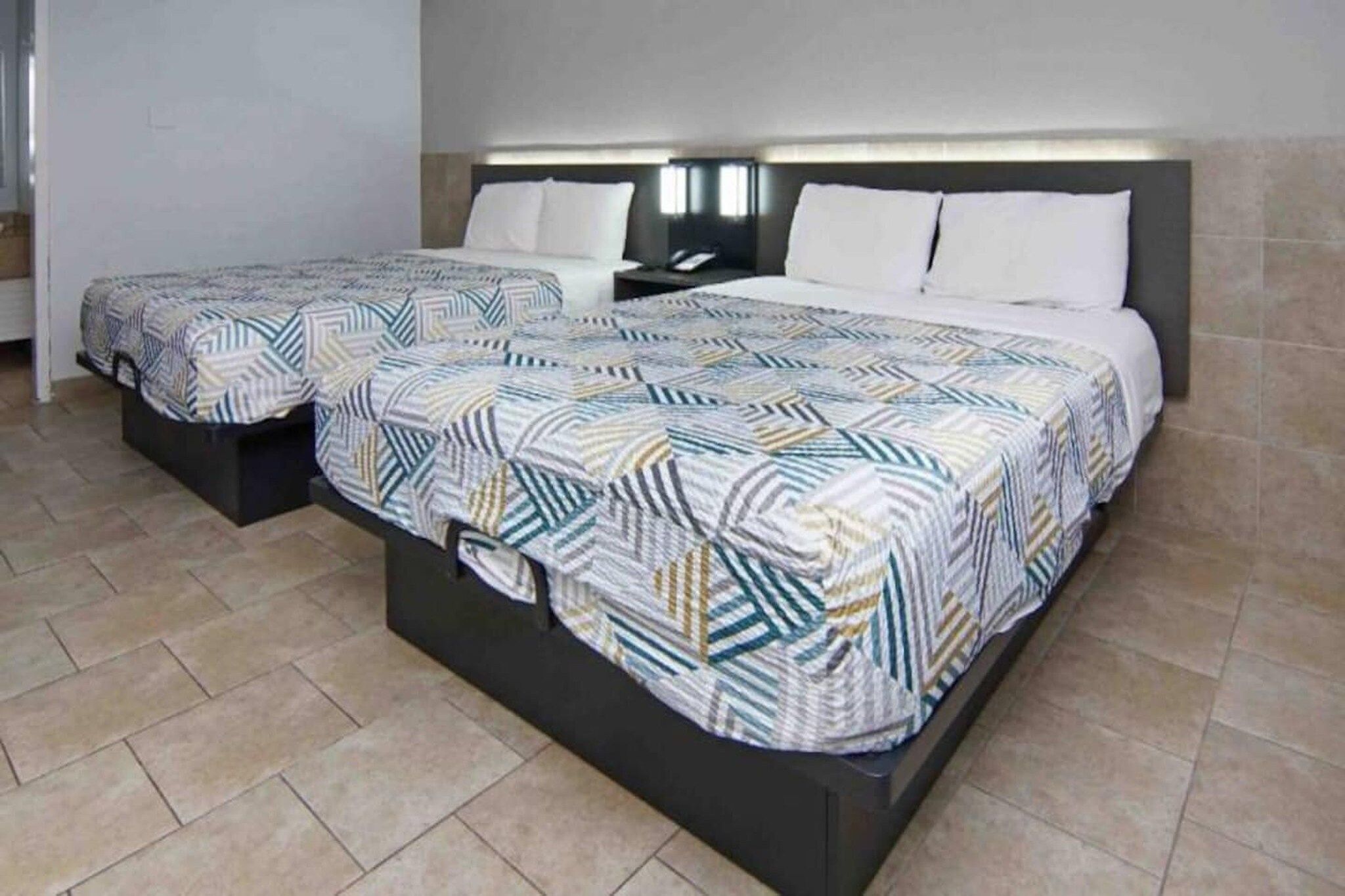 Een tweepersoonsbed met een gebedruid sprei en twee nachtkastjes.
