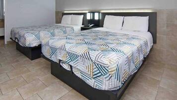 Een tweepersoonsbed met een gebedruid sprei en twee nachtkastjes.