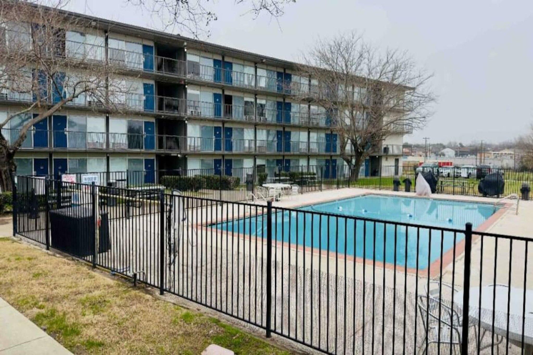 A multi-story building with a fenced swimming pool area.