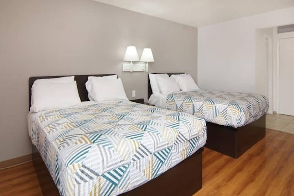 Habitación de hotel con dos camas, cada una con cubrecama estampado, mesita de noche y lámparas de pared.