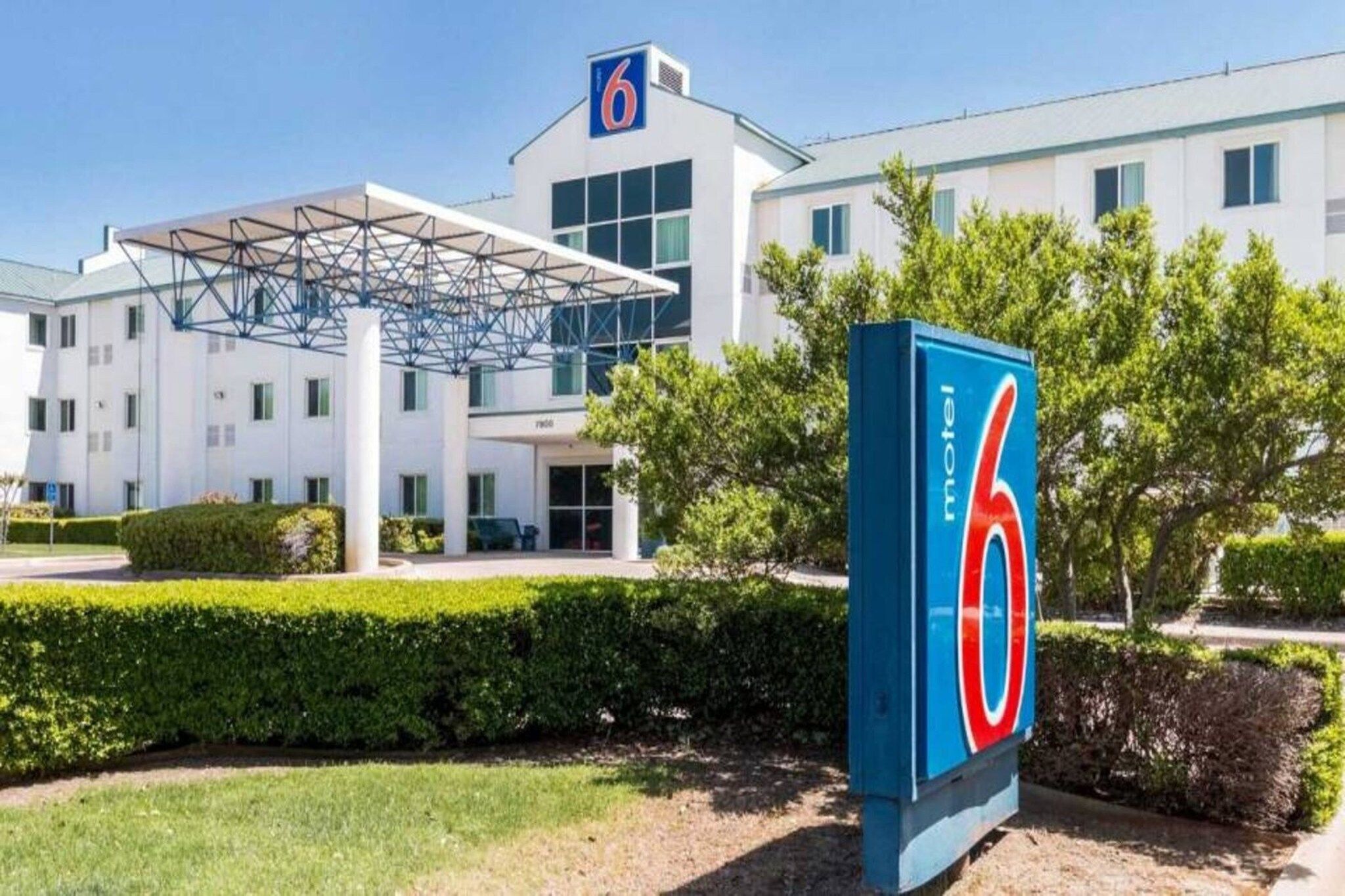 A motel with a large '6' sign, a covered entrance, and a modern building facade.