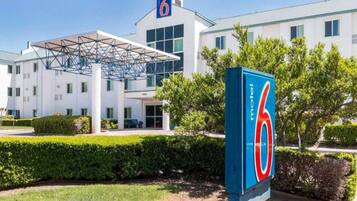 A motel with a large '6' sign, a covered entrance, and a modern building facade.