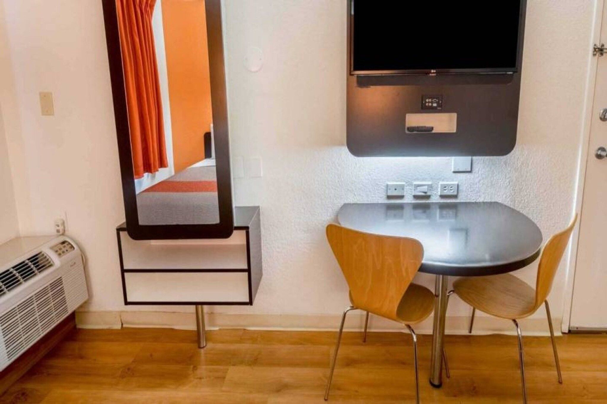 A room with a small table and two chairs, a wall-mounted TV, and a heater.