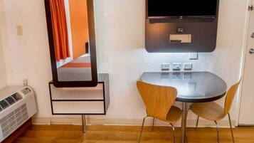 A room with a small table and two chairs, a wall-mounted TV, and a heater.