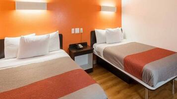 A hotel room with two beds, a nightstand, and a wall-mounted light fixture.