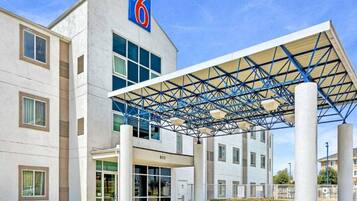 A modern hotel with a prominent '6' logo, a covered entrance, and a series of windows.